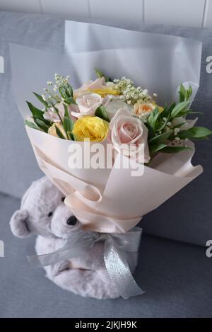 Un adorable ours en peluche et un bouquet de fleurs Banque D'Images