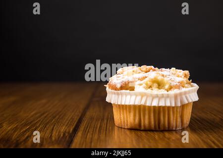 A muffin on a wooden table near gray wall with space for text Stock Photo