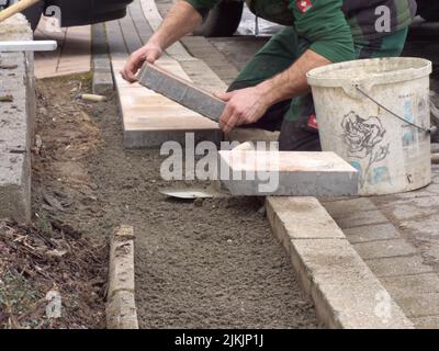 A man laying paving slabs on cement sand. Stock Photo
