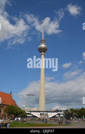 A vertical shot of the Berliner Fernsehturm against blue sky in bright sunlight at Alexanderplatz, Berlin, Germany Stock Photo