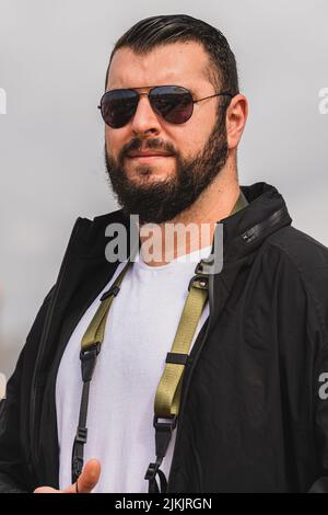 Photo verticale d'un jeune homme à barbe avec lunettes de soleil Banque D'Images