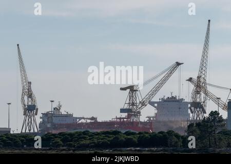 The Lisnave shipyard company repairing cargo ships and cranes in the background in the port of Setubal, Portugal Stock Photo