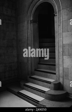 A vertical shot of a spiral stone staircase framed by an arched stone doorway Stock Photo