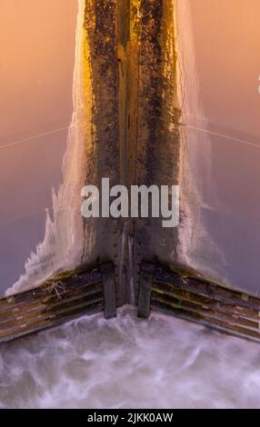 A vertical shot of water going out slowly at one of the biggest sluice gates in the Netherlands Stock Photo