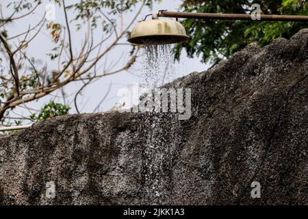 A water pouring from an old outdoors shower Stock Photo