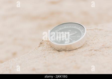 Gros plan, boussole analogique sur le sable indiquant la direction, le concept de voyage, l'été, la mise au point sélective. Banque D'Images