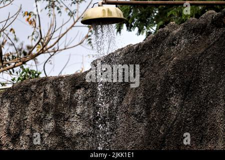 A water pouring from an old outdoors shower Stock Photo