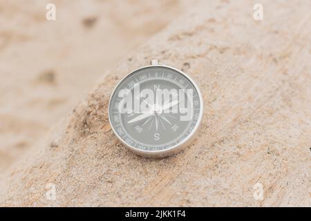 Gros plan, boussole analogique sur le sable indiquant la direction, le concept de voyage, l'été, la mise au point sélective. Banque D'Images