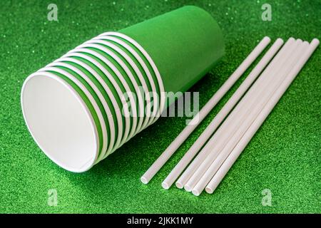 A closeup shot of multiple green paper cups with several straws on a green background Stock Photo