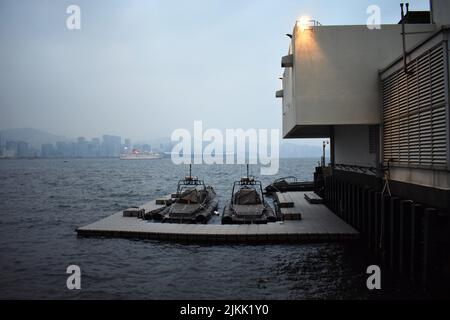 A scenic view of boats moored at harbor against a ship sailing in the seascape on a foggy day Stock Photo