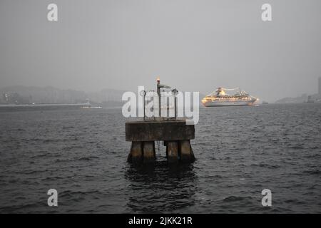 A scenic view of the harbor against a ship sailing in the seascape on a foggy day Stock Photo