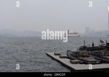 A scenic view of boats moored at harbor against a ship sailing in the seascape on a foggy day Stock Photo