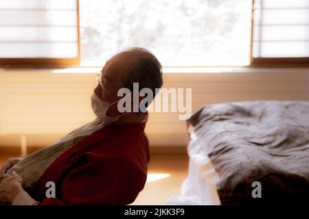Un homme asiatique âgé dans un masque assis à l'hôpital Banque D'Images
