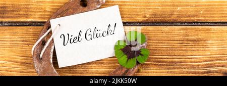 horseshoe avec le signe vert shamrock pour la chance sur un fond en bois avec le texte allemand viel glück, en anglais bonne chance Banque D'Images