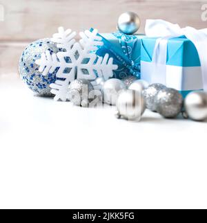 Boules d'argent sur l'arbre de Noël et cadeaux de Noël en emballage festif avec rubans sur une table en bois blanc. Image en tons, mise au point sélective Banque D'Images