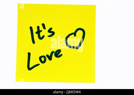 A black colored inspirational motivating quote "it's love" on a yellow post-it over a white background Banque D'Images