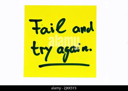A black colored inspirational motivating quote on a yellow post-it saying "Fail and try again" Banque D'Images