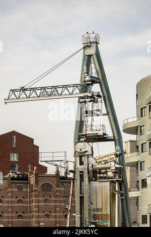 Old crane at the edge of former factory seen in the background with modern architecture around in Utrecht at Leidsche Rijn canal Stock Photo