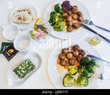 Moscou, Russie, novembre 2018: Nourriture pour deux au restaurant IKEA: Assiettes avec boulettes de viande avec sauce et brocoli, tasses et sachets de thé, salade avec crevettes, Banque D'Images