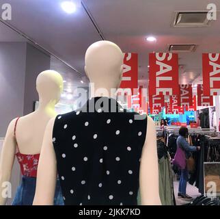Moscou, Russie, juillet 2019: Deux mannequins chauves femelles se tiennent dans un magasin de vêtements parmi les marchandises et regardez vers le bas les acheteurs et beaucoup de bannières rouges o Banque D'Images