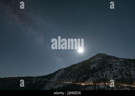 A beautiful shot of the sunrise in the background of a mountain partly covered in snow. Stock Photo