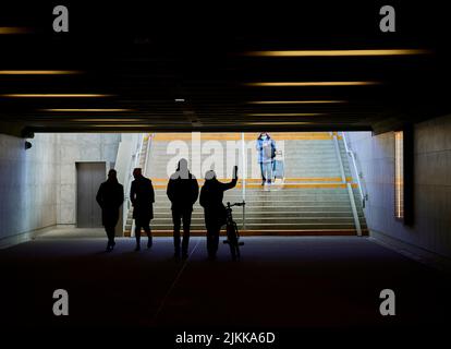 A closeup of People walking in an underground passage leading to stairs in the sunlight Banque D'Images