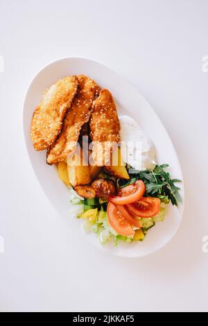 A top view of crispy fried chicken nuggets with potatoes and vegetables on a table Stock Photo