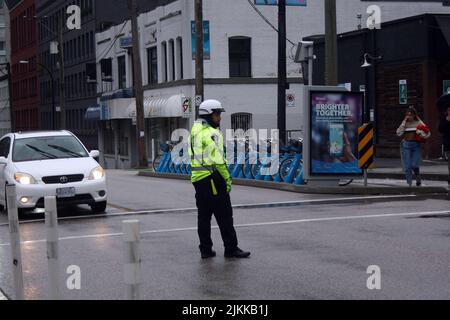 A police officer standing at the intersection of the street to regulate traffic in Vancouver, Canada Stock Photo