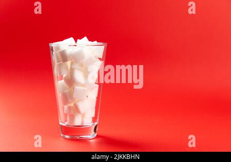 verre avec cubes de sucre sur fond rouge Banque D'Images