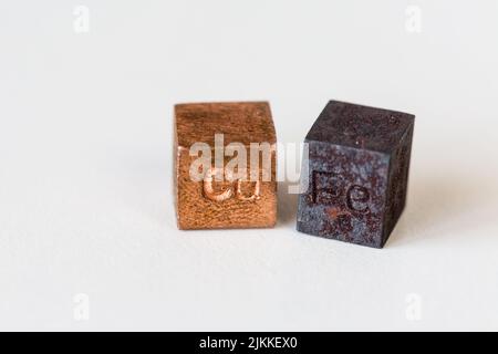 Les cubes en fer et en cuivre portent des noms d'éléments sur fond crème Banque D'Images
