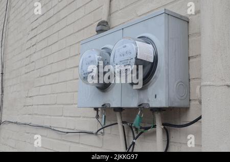 A selective focus shot of grey electricty meters on a white brick wall Banque D'Images