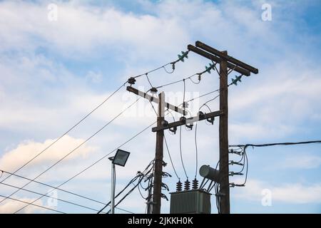 A electric poles with wires with a cloudy sky on the background Banque D'Images