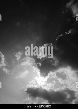 A vertical low angle grayscale shot of the sky with cumulus clouds Stock Photo