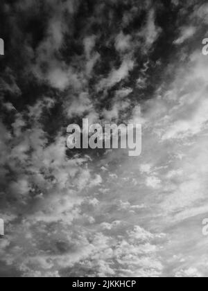 A vertical low angle grayscale shot of the sky with cumulus clouds Stock Photo