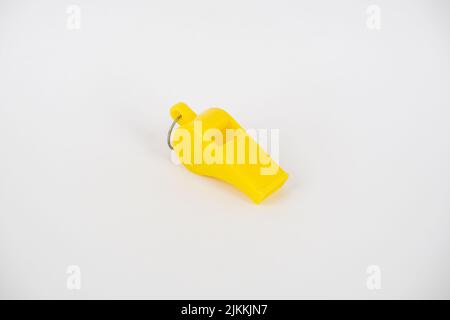 A close-up shot of a yellow whistle isolated on a white background Stock Photo