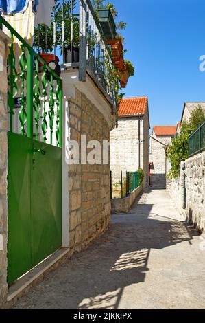 A vertical shot of a cute stone building with green gates on a narrow street in Split, Germany Stock Photo