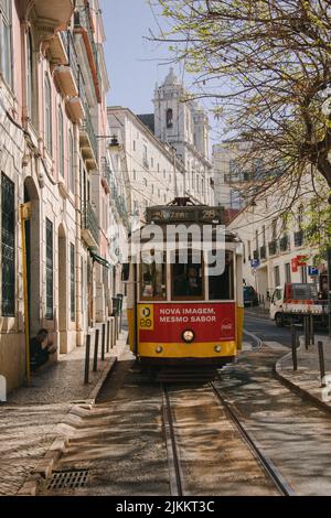 A vertical shot of a red and yellow Tram  passing through Lisbon city in Portugal Stock Photo