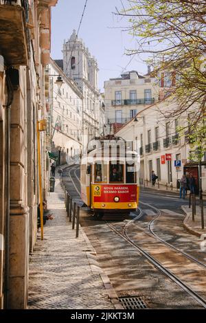 A vertical shot of a red and yellow Tram  passing through Lisbon city in Portugal Stock Photo