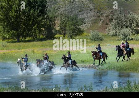 Soldats AMÉRICAINS vêtus d'uniformes de cavalerie à cheval traversant la rivière Little Bighorn pendant la reconstitution du dernier stand de Custer, Montana Banque D'Images