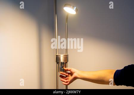 Hand of a woman turning on a lamp in a house with white background Stock Photo