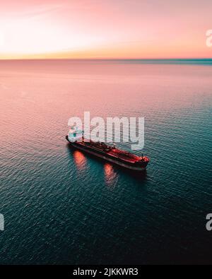An Aerial shot of a red tanker cargo ship on the sea during sunset Banque D'Images