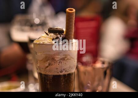 A closeup shot of a glass of coffee cocktail with a waffle tube on blurry background Banque D'Images