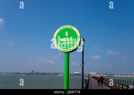 Un marqueur de 1,5 kilomètre sur Southend Pier lors d'une journée ensoleillée à Southend on Sea, Essex, Royaume-Uni. panneau à 1,5 kilomètre, avec les personnes qui marchent sur la passerelle Banque D'Images