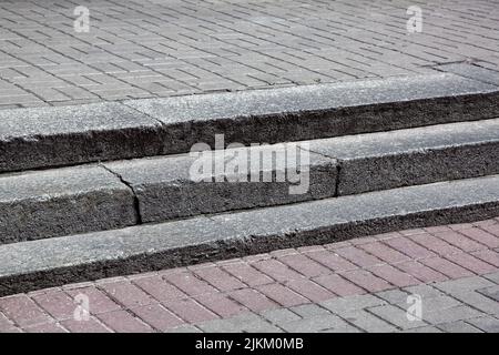 Marches de granit gris au milieu de la pierre pavée de rue pavée de brique, gros plan de paysage urbain par temps ensoleillé, personne. Banque D'Images