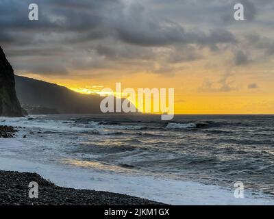 Une vue panoramique sur les vagues fortes sur la plage au coucher du soleil Banque D'Images