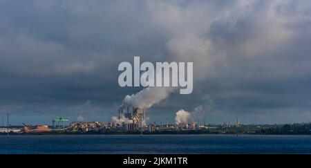 A factory with smoke coming out from industrial pipes captured from the sea Stock Photo