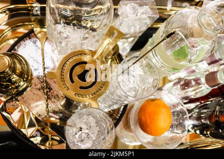 Cocktail Hour - saupoudreuse de martini sur plateau avec différents verres et bouteilles de cristal et une orange - vue du dessus et mise au point sélective Banque D'Images