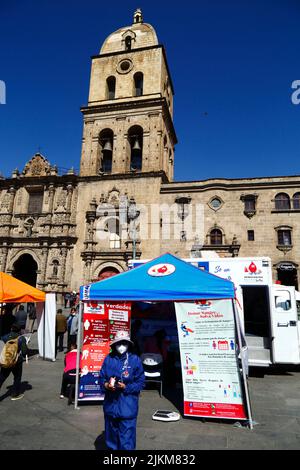 Plaza San Francisco, la Paz, Bolivie. 2nd août 2022. Un médecin se tient à l'extérieur d'un centre de collecte mobile où les gens peuvent donner du sang, un service organisé par les autorités sanitaires de la Paz. Les banques de sang boliviennes comptent beaucoup sur les dons de bénévoles et de centres de collecte comme celui-ci sont courants dans la ville, en particulier pendant les périodes de vacances ou lorsqu'il y a des pénuries. Derrière se trouve l'église de San Francisco, l'église coloniale la plus importante et la plus impressionnante de la ville. Banque D'Images