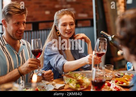 Portrait d'une jeune femme qui apprécie un verre de vin tout en célébrant avec des amis lors d'un dîner-fête Banque D'Images