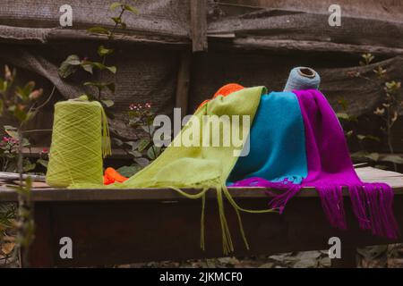 A closeup shot of the colorful sewing threads and scarves on the wooden table Stock Photo